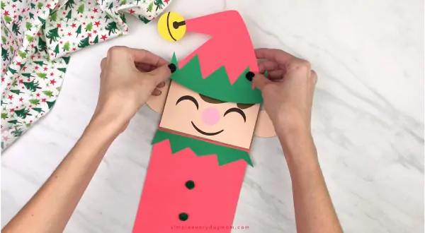 hand gluing hat to paper bag elf craft