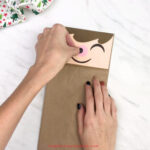 hand gluing nose to paper bag elf craft