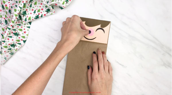 hand gluing nose to paper bag elf craft