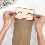 hand gluing face to paper bag elf craft