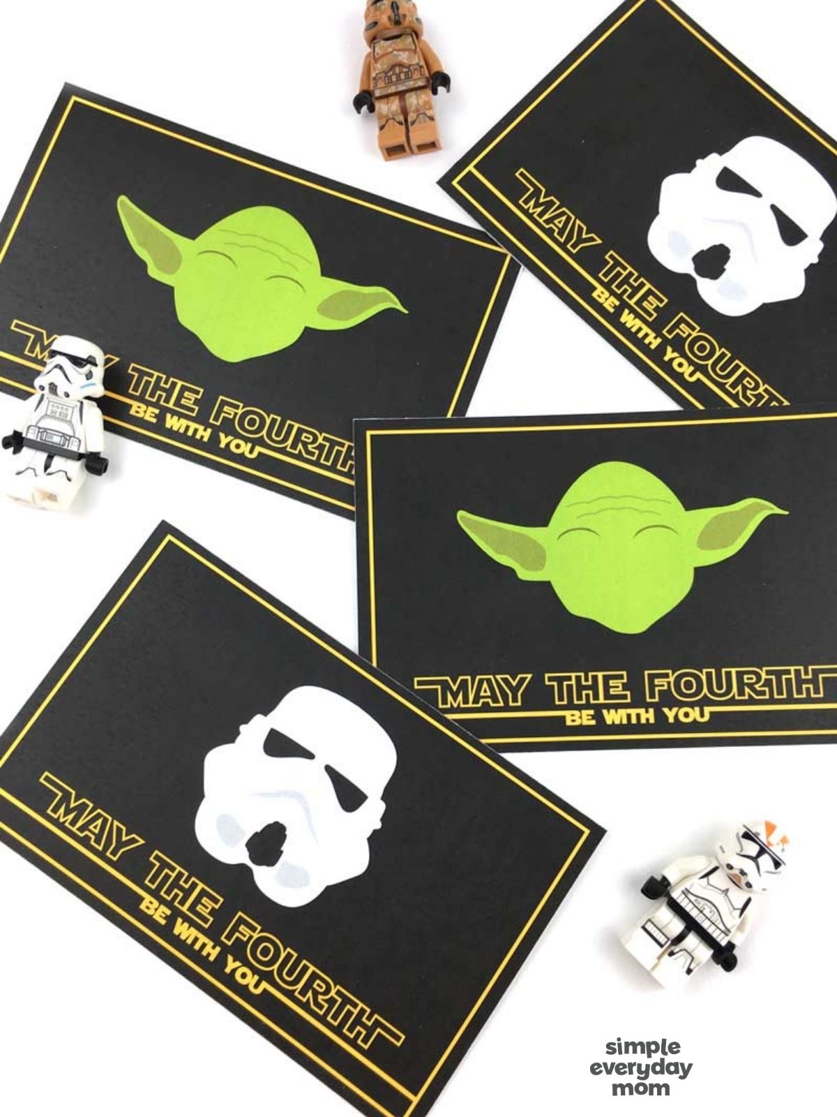 Close-up of Star Wars-themed “May the Fourth be with you” cards featuring Grogu and stormtrooper helmet designs with small toy figures nearby.