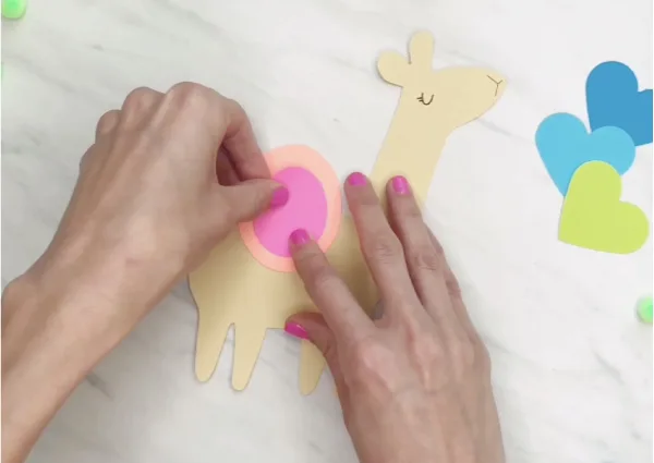 hand gluing pink paper onto llama craft