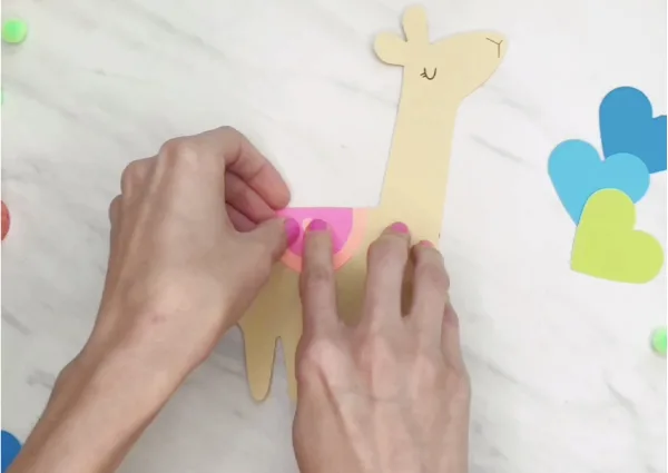 hand gluing heart onto llama craft