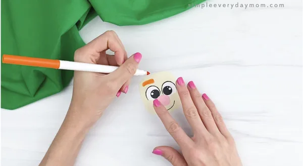 hand drawing eyebrows onto handprint leprechaun face