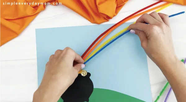 hand gluing pipe cleaners to pot of gold craft