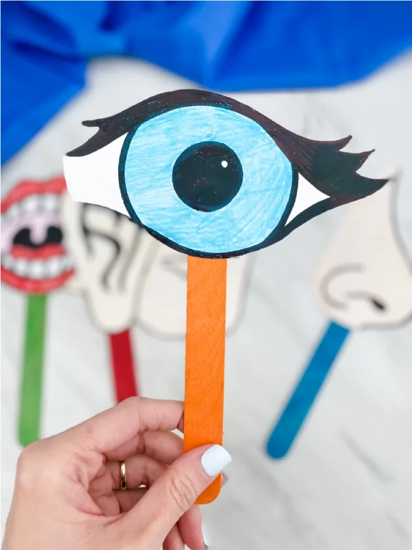 hand holding eye puppet with others in the background