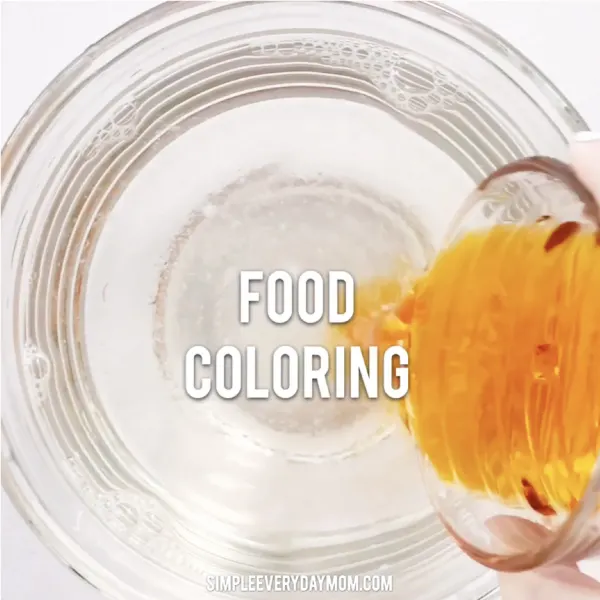 hand pouring food coloring into bowl