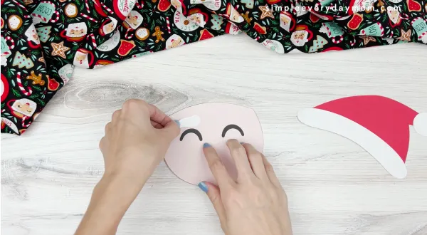 hand gluing eyebrow to Santa handprint craft