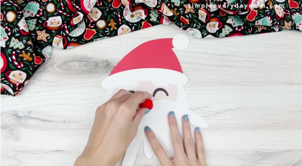 hand gluing pom nose to Santa handprint craft