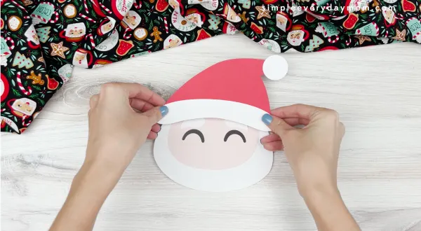 hand gluing hat to Santa handprint craft