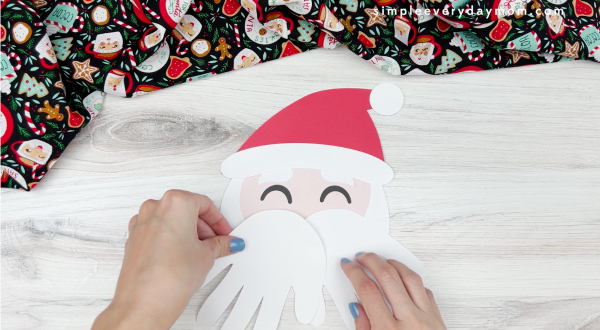 hands gluing handprint beard to Santa craft