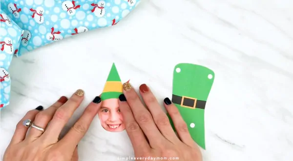 Hands gluing Buddy the elf hat to kids photo