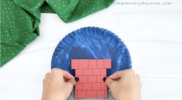 hand gluing chimney to blue paper plate