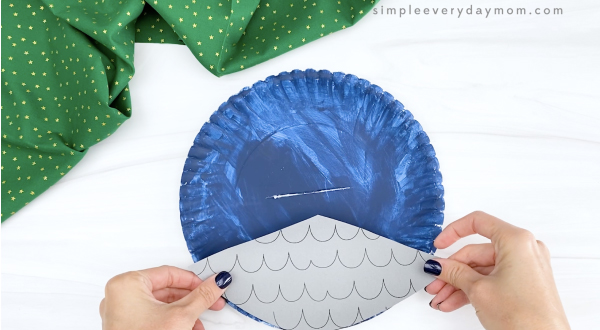 hand gluing roof to blue paper plate