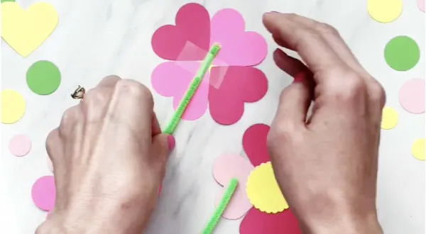 hand taping pipe cleaner stem to paper flowers