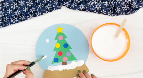 hands painting puffy paint onto snow globe craft