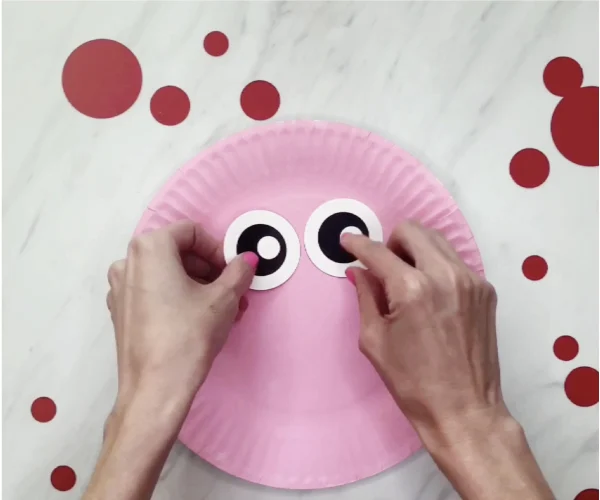 hand gluing eyes to paper plate pig craft