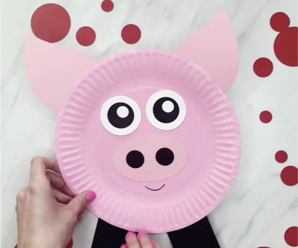 hand gluing feet to paper plate pig craft