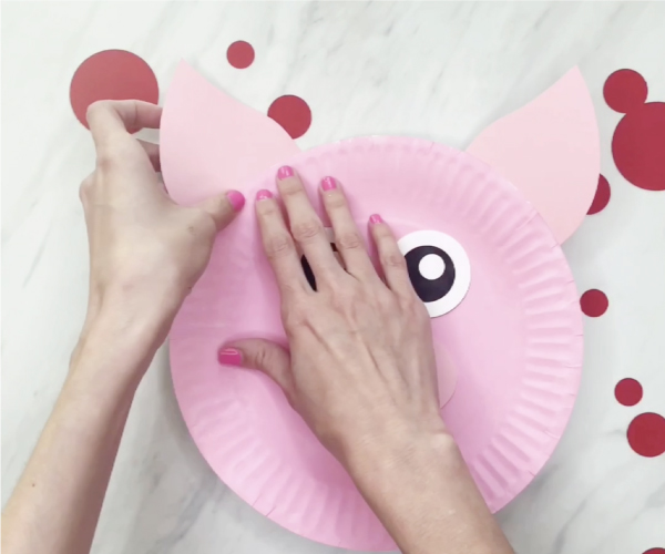 hand gluing ears to paper plate pig craft