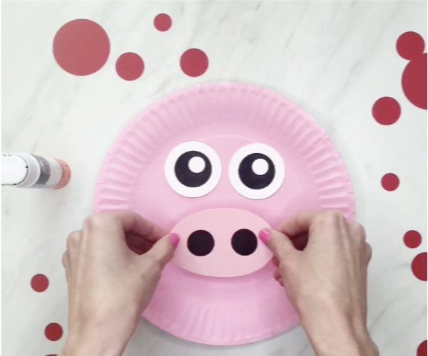 Hand gluing nose to paper plate pig craft
