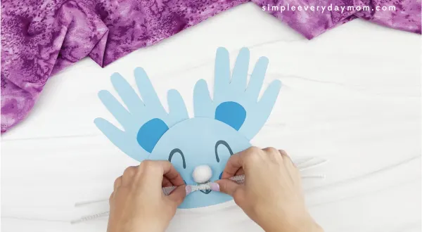 hand gluing white pipe cleaners to handprint bunny craft