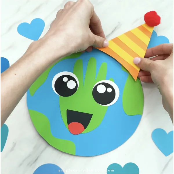 hand gluing party hat to Earth craft