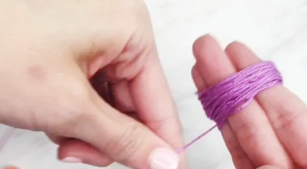 hands wrapping embroidery floss around 3 fingers