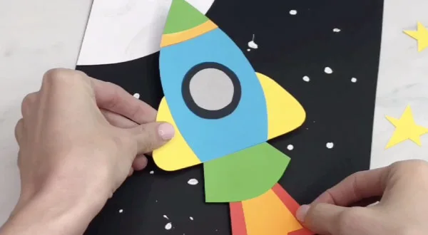 hand gluing rocket to space background