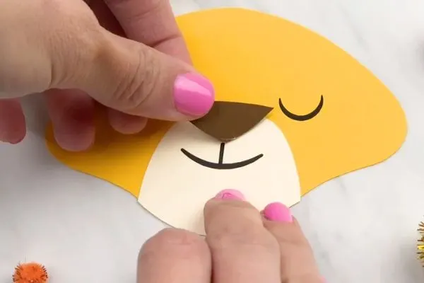 hand gluing brown nose to lion paper craft