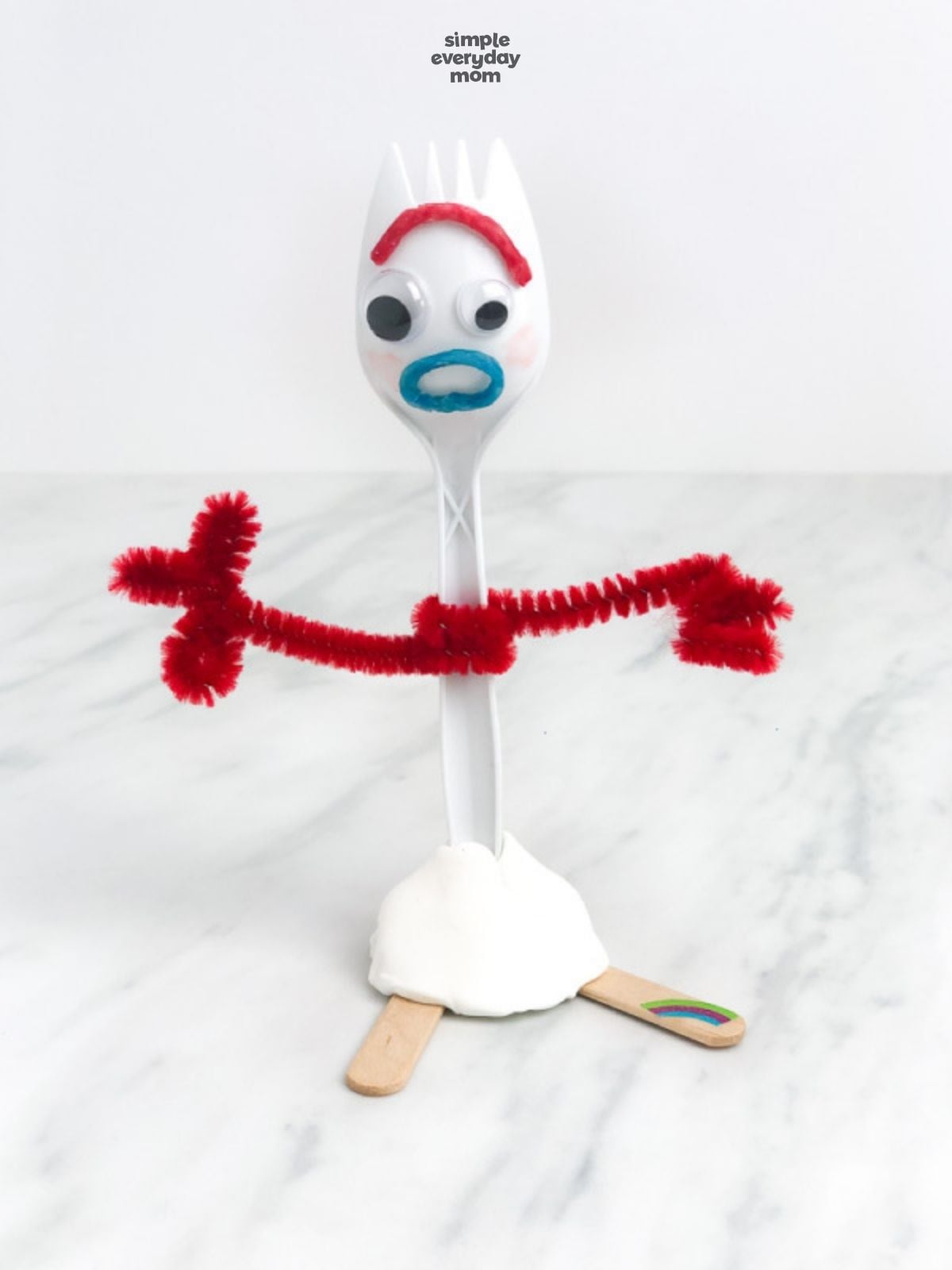 Finished Forky craft with red pipe-cleaner arms stretched outward and a rainbow sticker on one foot.