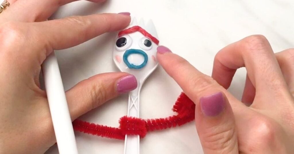 Hand adding pink blush to the cheek of the Forky craft.