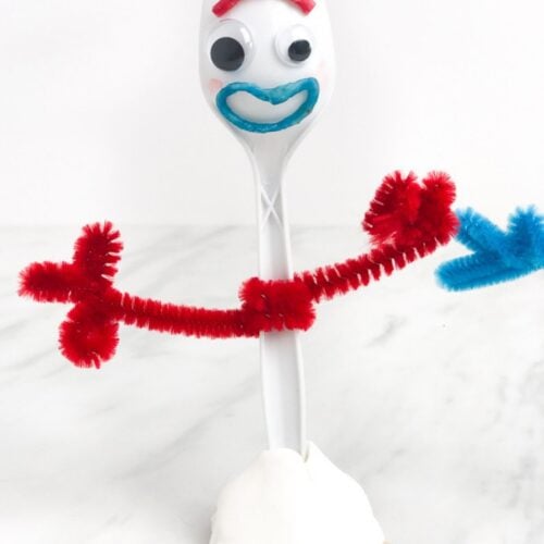 Finished Forky craft with red pipe-cleaner arms, googly eyes, a blue mouth, clay base, and craft-stick feet.