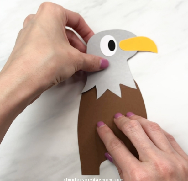 hand gluing head to handprint eagle craft