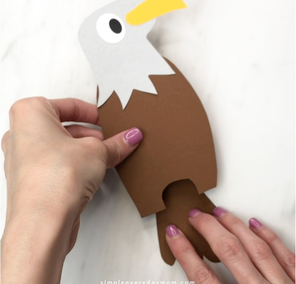 hand gluing tail feathers to handprint eagle craft