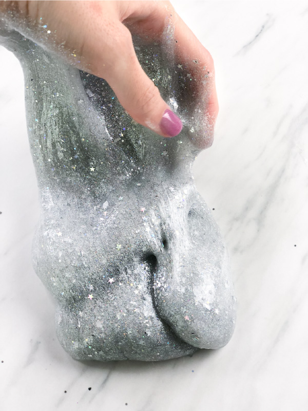 woman's hand holding silver glitter slime