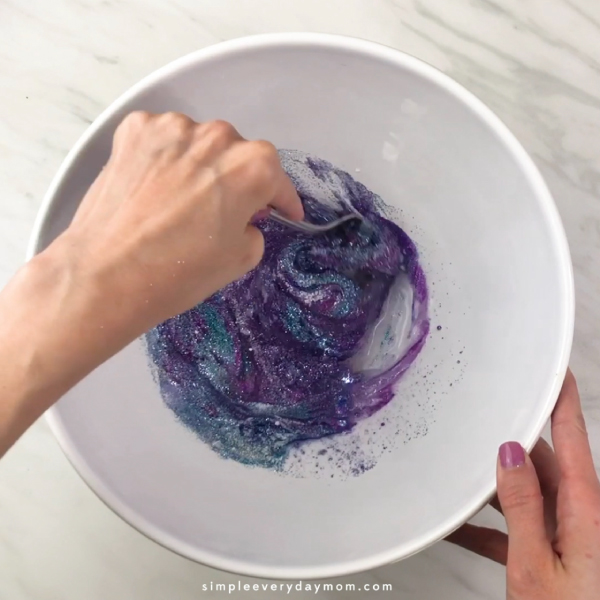 hands mixing slime ingredients with a fork