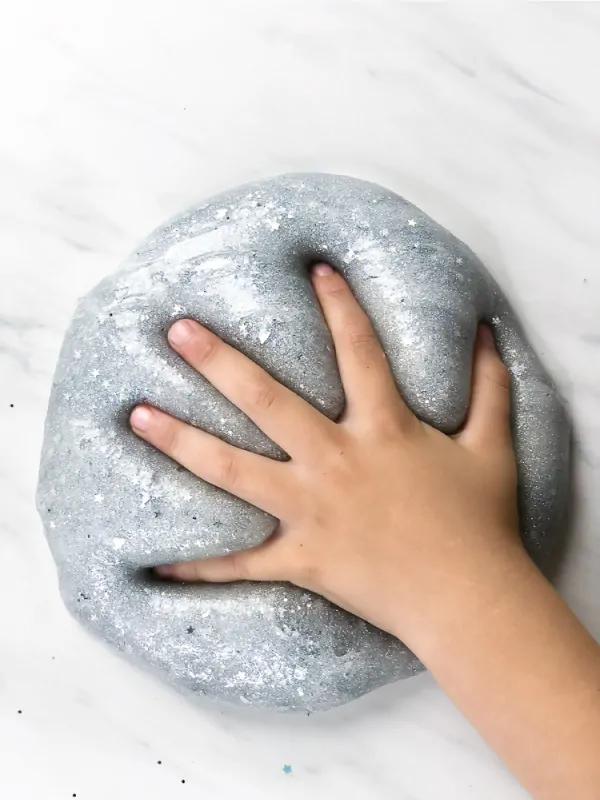 child's hand in silver glitter slime 
