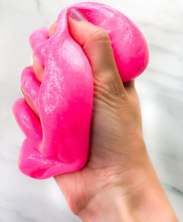 hand squeezing neon pink slime