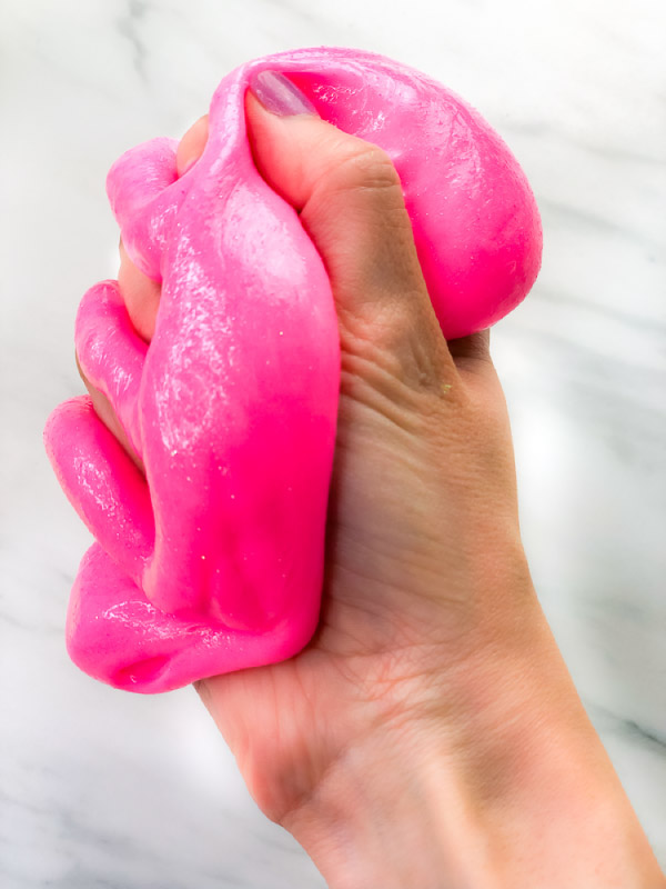 hand squeezing neon pink slime