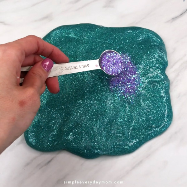 hand pouring purple glitter onto slime