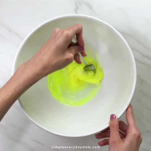 hand mixing neon slime with a fork
