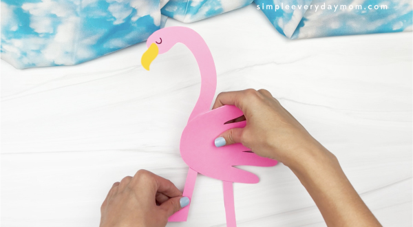 hand gluing legs to flamingo handprint craft