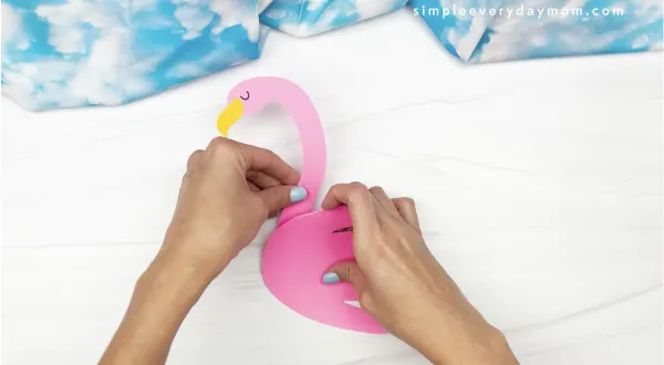 hand gluing handprint body to flamingo handprint craft