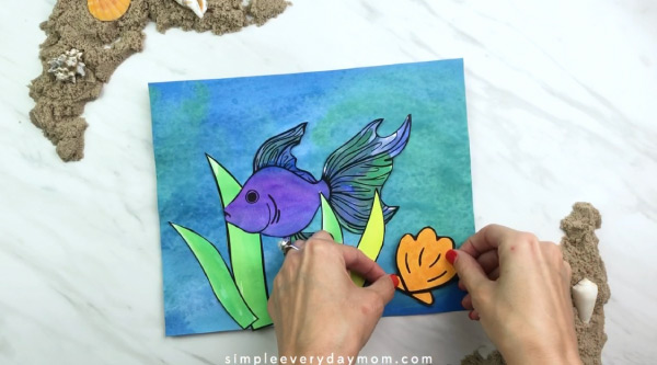 hand gluing seashell to fish painting