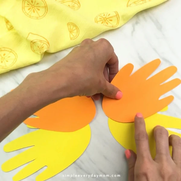 hands arranging child's paper handprints in the position of butterfly wings 