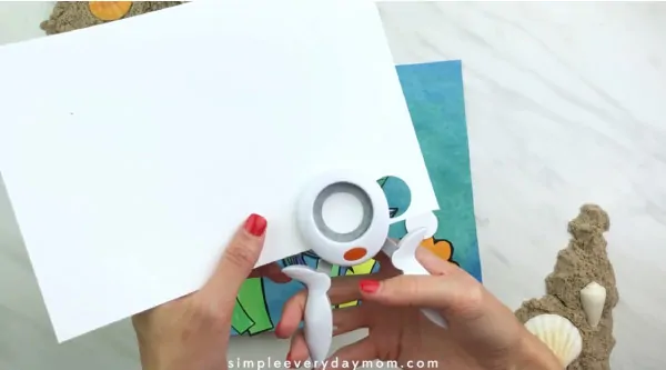 hand punching circles from white paper