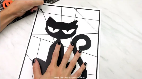 hands using black marker to outline black cat craft
