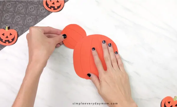hands gluing ears onto pumpkin for Mickey Mouse