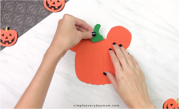 hands gluing pumpkin stem onto pumpkin