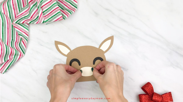 hands gluing muzzle to reindeer face